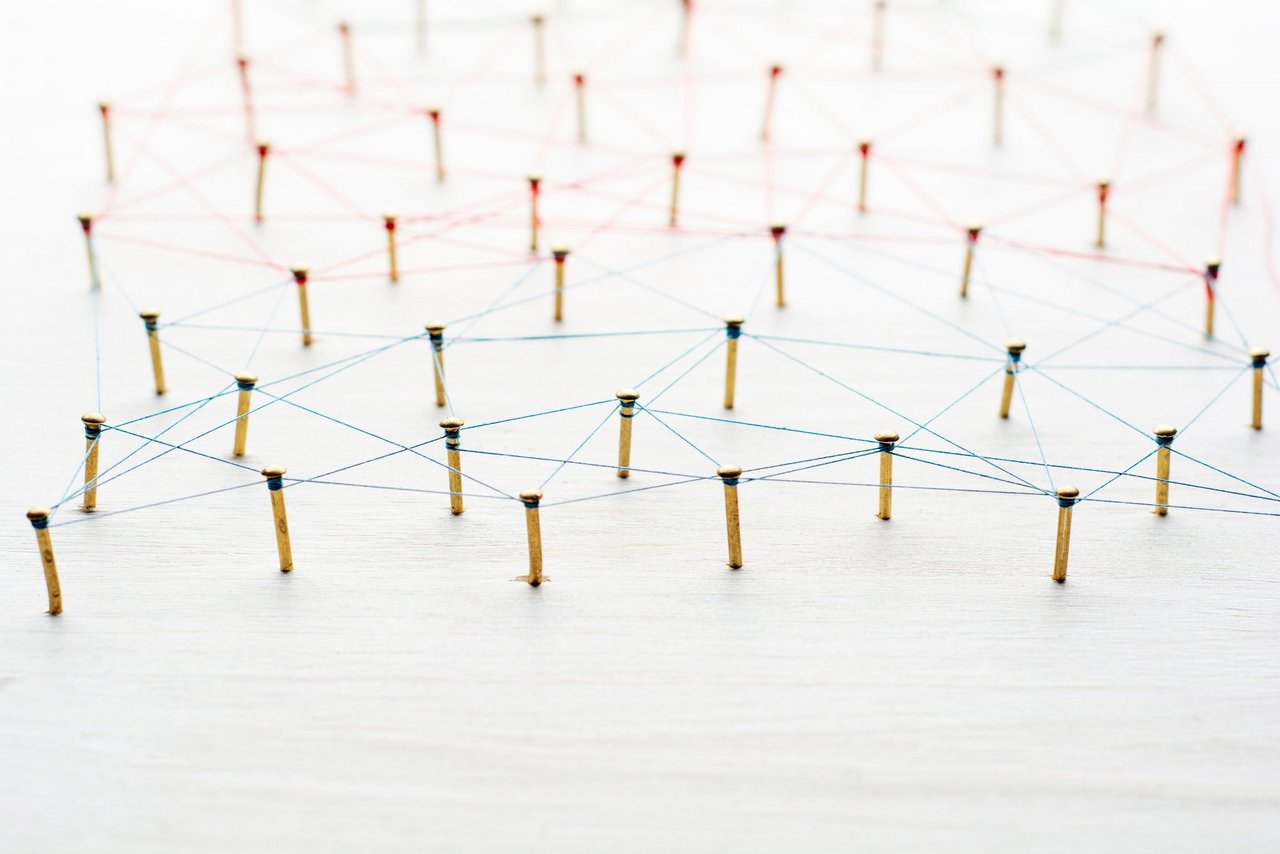 Background with selective focus. Abstract concept idea of network, social media, internet, teamwork, communication. Thumbtacks linked together by red thread. Isolated. Entities connected