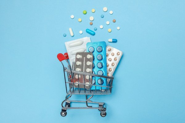 Shopping basket and pills in blisters. The concept of buying drugs online, delivery of medical devices