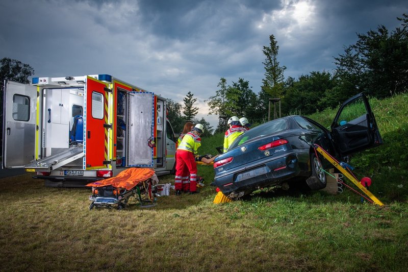 Rettungssanitäter bergen eine verletzte Person aus einem Auto